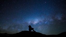 silhouette of man looking up at stars