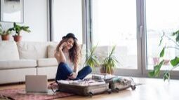 young woman on phone packing for a trip