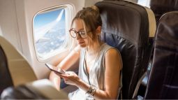 traveler on airplane using phone